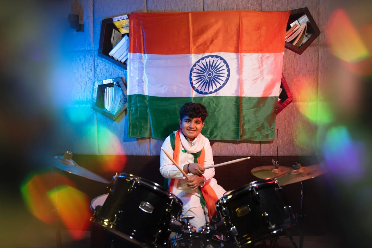 Hridan at his drum kit with an Indian flag displayed behind him