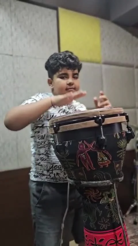 Hridan playing a hand drum in the music studio